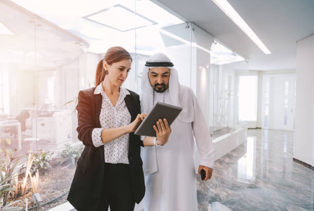 Business professionals discussing documents on a tablet in a modern office within RAKEZ Free Zone.