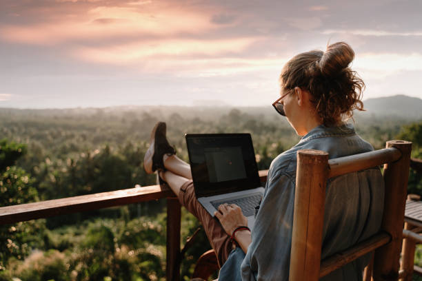 Person working on a laptop outdoors with a scenic view, suggesting ways to boost holiday business.