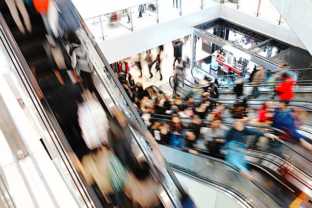 Busy shopping mall with people on escalators, reflecting the hustle of year-end activities for small business owners.